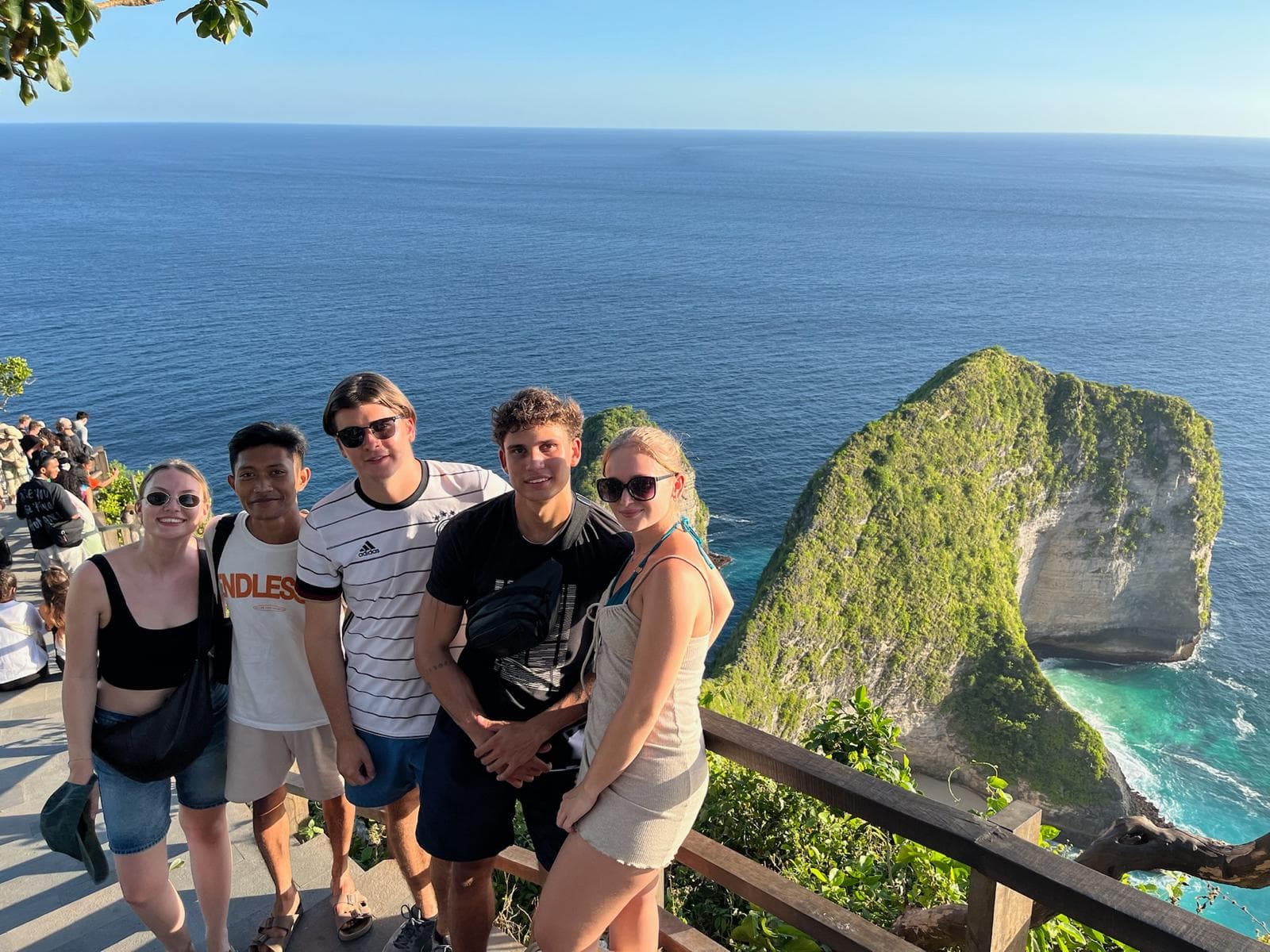 A group of people posing together at a coastal cliff viewpoint overlooking the ocean