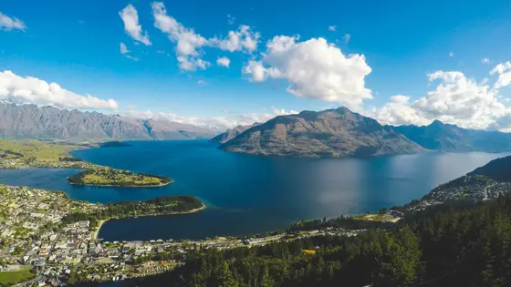 Queenstown and Lake Wakatipu below mountains under a blue sky, New Zealand