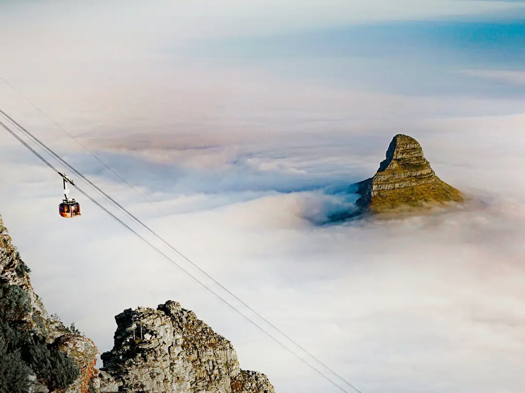 A cable car above a sea of clouds with Lion's Head rising behind it, Cape Town