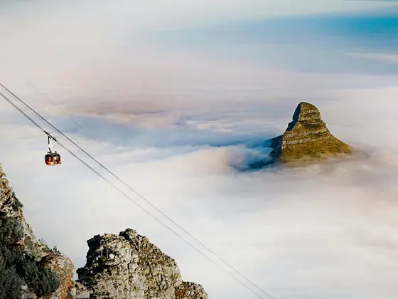 A cable car above a sea of clouds with Lion's Head rising behind it, Cape Town