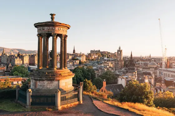 The Dugald Stewart Monument on Calton Hill overlooking the Edinburgh skyline at golden hour