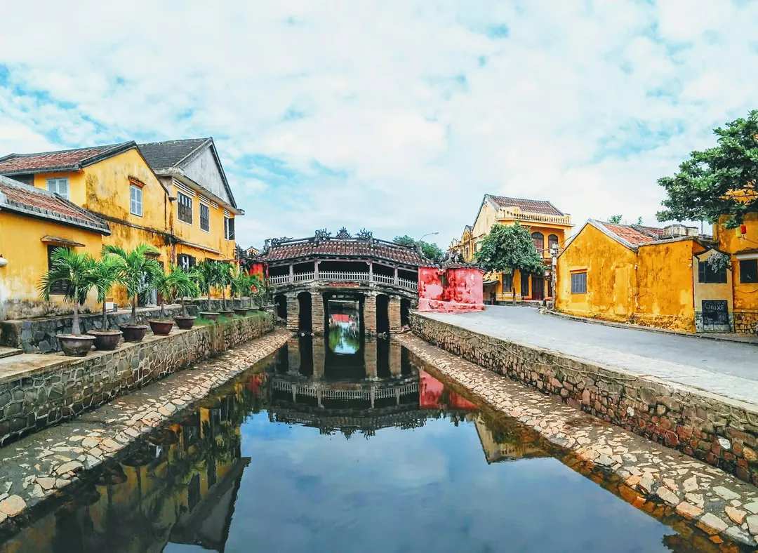 The Japanese Covered Bridge and yellow houses along a canal in the old town of Hội An, Vietnam
